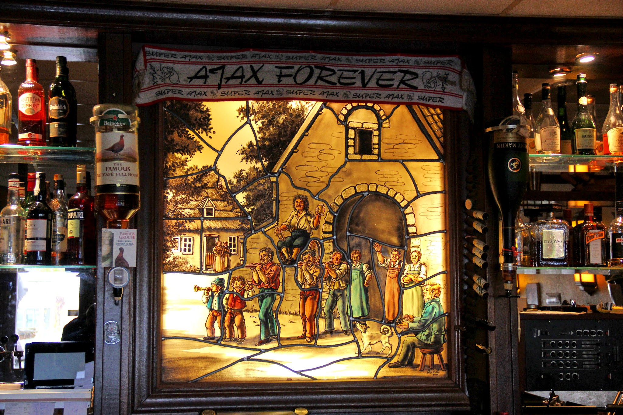 De bar van Full House met warm verlicht glas-in-lood en flessen aan weerszijden