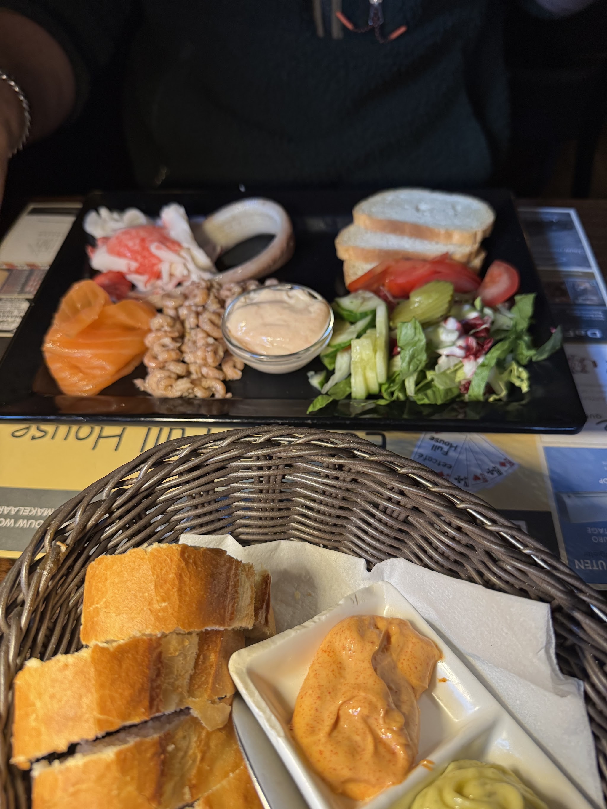 Een schaal met vis, salade en brood op tafel