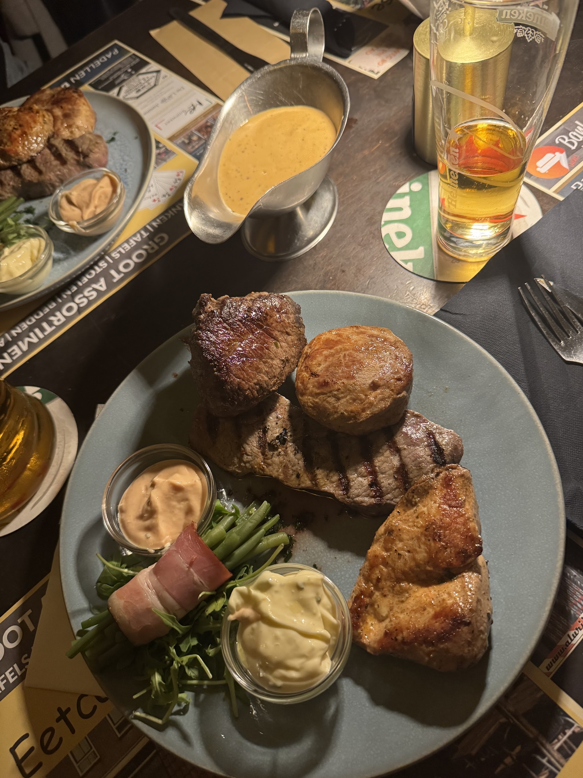 Een bord met verschillende gegrilde vleesgerechten en saus
